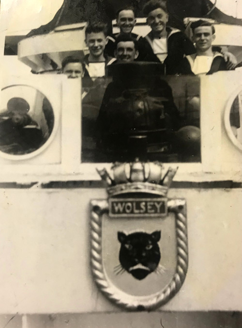 Shipmates pose with ship's crest, HMS Wolsey